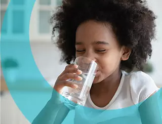 Petite fille qui boit un verre d'eau